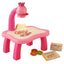 Pink children's art table with a projector and accessories on a brown background