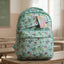 Light blue backpack with butterfly pattern on a wooden table in a classroom.