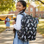 Girl with a black backpack featuring white animal prints on a schoolyard background