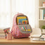 Pink backpack with books on a desk in a bright room