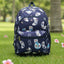 Navy blue backpack with colorful patterns on grass with palm trees in the background