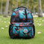 Backpack with colorful design on grass with palm trees in the background