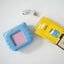 Blue device with pink screen, USB cable, and two boxes on a white background