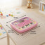 Pink toy keyboard with measurements on a table with toys in the background