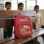 Red backpack with cartoon character on a wooden bench in a classroom setting