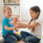 Two children playing with a colorful toy in a room with a bookshelf in the background.