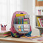 Backpack with stationery items on a desk in a classroom setting