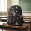 Backpack with space-themed design on a desk in a classroom