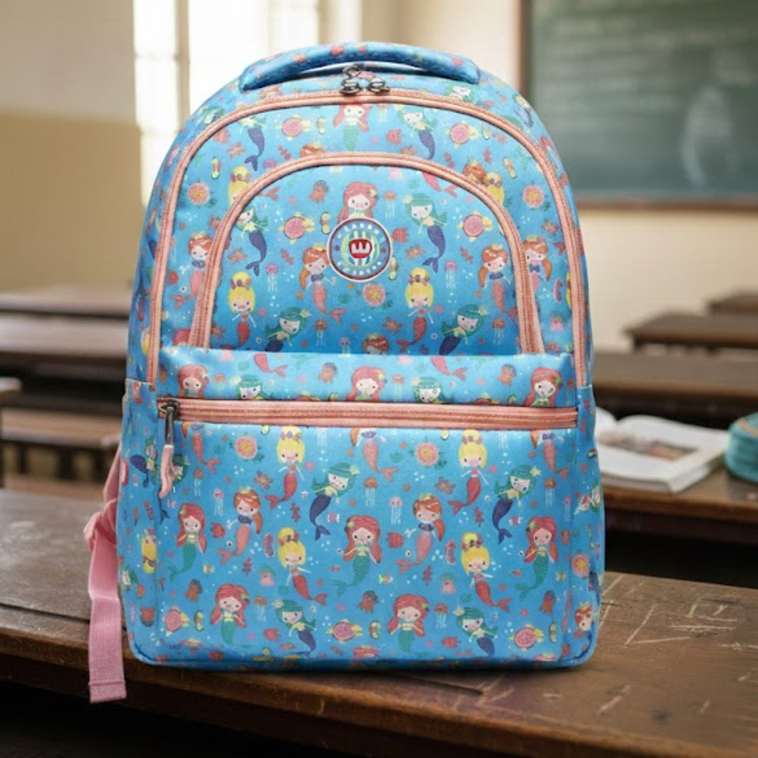 Blue backpack with cartoon characters on a wooden desk in a classroom.