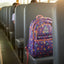 Colorful backpack on a school bus seat with sunlight streaming through the windows.